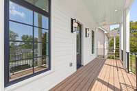 Gorgeous and unique Charleston-style curb appeal features spacious double front porches, custom railings, designer exterior light fixtures and landscaping with reclaimed stone from build site.