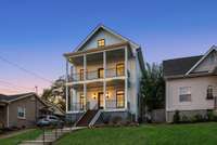 Gorgeous and unique Charleston-style curb appeal features spacious double front porches, custom railings, designer exterior light fixtures and landscaping with reclaimed stone from build site.