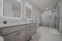 Floor-to-Ceiling Tile Takes this Bathroom to Above and Beyond. One of the most unique details is the Chevron pattern stone tile inlay.  Duel Showerheads.