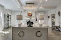 From recessed lighting to statement chandeliers, to a coffered ceiling, this living room has it all!