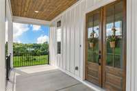 The view of the front covered porch accenting the iron hand rails and 8 foot tall wooden double doors. Bring your comfy chairs or porch swing and enjoy the serene views that this porch has to offer.