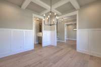 This dining area is adorned with wainscoting and a coffered ceiling. The butlers pantry is perfectly placed for entertaining.