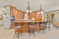 A chef’s dream kitchen with a gracefully large, curved island, beautiful custom wood cupboards, with expansive counter space of complementary granite. Separate large pantry, with floor-to-ceiling shelves.