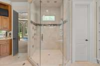 Large tiled & glass shower with brass “waterfall feature”, with dual controls from ceiling and two sides.