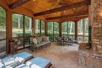 A large screened in porch with two all-weather ceiling fans and travertine tile.