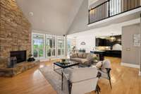 The living room features a stacked stone fireplace, vaulted ceiling, and view of the beautiful kitchen