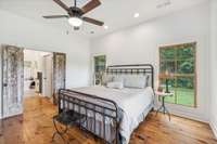 This primary bedroom is equipped with a ceiling fan, rustic hardwood floors, double windows, and recessed lighting. 5901 Givens Rd Lascassas, TN 37085