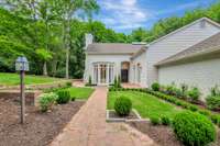 Front entry of house brick sidewalk and boxwood lined courtyard.