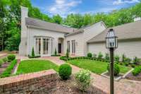 Freshly painted white brick and clapboard exterior with handsome post lantern at edge of driveway.