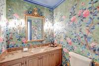 Second powder room off entry with custom wallpaper and beautiful crystal sconces.