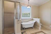 Huge primary bath features oversized shower with built in seat, beautiful claw foot tub and custom tile.