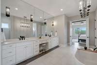 Large wall of cabinetry, double vanities and sitting area