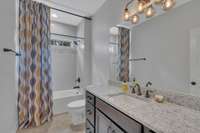 Hall bathroom upstairs features plenty of storage, granite countertops, rectangular sink, and shower/tub combo with transom window.