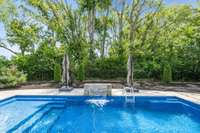 The pool offers a water feature, tanning ledge and benches, all backing up to the tree-lined setting of Granbery Park.