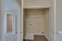 Laundry room is located between primary bedroom and second bedroom for easy access.