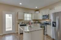 Here's a view of your kitchen showing all the cabinets with lots of sunlight from the window and door that leads to the fenced in patio.