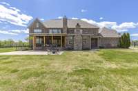 Back of home with covered porch and wood burning fireplace.