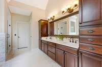 Tile and stone primary bathroom features double vanities and plenty of storage