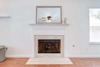 Gas Fireplace with Marble Surround, Wood Fireplace Mantel.  TV Outlets are behind the mirror. 2-inch blinds on window to the right.