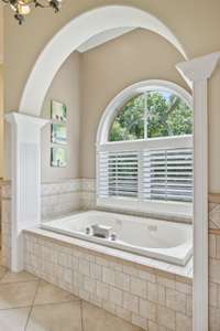 The Millwork and Tile design around this Arched Alcove make it the perfect setting for a relaxing soak. It has natural light coming through the Plantation Shutters of the Arched Window.