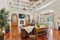 From the Kitchen looking through the Great Room, you can see the Beauty of how the Tigerwood Floors blend with the built-in Arched Cabinets, Crowned by a 16-Foot Coffered Ceiling with Double Fans.