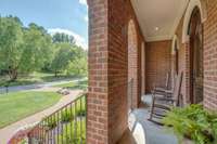 Note the custom build details from triple bricked archways to a trio of wood doors offering access to this front porch.