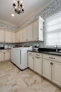 The oversized laundry room has incredible cabinet storage, sink and tiled floor