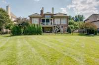 Exterior photo of the back of this impressive estate.  Evergreens provide a privacy screen around the hot tub area.