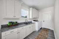 Large laundry room has plenty of cabinet & counter space, sink, & tile flooring