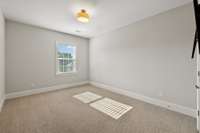 Bedroom #4, also located on the Upper Level, includes plush carpet, walk-in closet, and a drum light fixture.