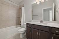 The private Bath features a storage vanity, tile flooring and tub/shower combo with tile surround.