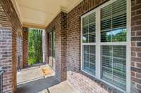 Enjoy a charming Covered Front Porch. Features include a painted wood ceiling with trim detail, brick steps with metal railing, lantern-style lighting, and space for rocking chairs to enjoy nice breezes.