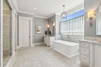 This luxurious primary bathroom boasts full custom inset bead hardwood cabinets with furniture-like features, adding elegance and functionality to the space.