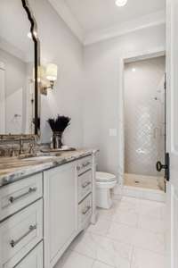 This spa-like en suite bathroom showcases exquisite Rohl fixtures and an Arabesque tiled shower equipped with two shower heads and a convenient seat.