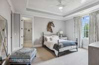 The stunning tray ceiling, adorned with shiplap inlay, adds a unique charm to this upstairs bedroom, complemented by custom cabinetry and extensive tile work in the en suite bath.