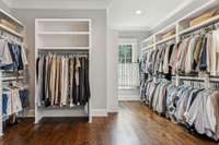 One of two primary bedroom closets offers built-in shelving, an island, mirror, and seating with soft-close drawers.