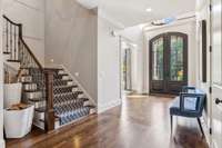 Note the impressive chevron-patterned hardwood flooring in the foyer, complemented by a grand two-story entryway featuring a display ledge and a stunning hand-hammered pewter railing.