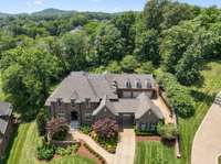 The property features commercial-quality brass landscape uplighting, an irrigation system, and meticulously designed landscaping, complemented by a three-car garage and an additional large one-car garage with access through the porte cochère.