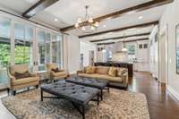 The living area is flooded with natural light through 10-foot tall, 12-foot wide Anderson sliding glass doors, while wood beam ceilings and hardwood flooring add warmth and elegance.