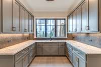 View of the Luxurious Main Laundry room with Custom Cabinetry and imported tile Backsplash