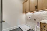 Upper level Laundry room with custom cabinetry and imported tile backsplash