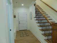 Entrance to garage with storage bench, cabinets, and broom closet on left and stairs up to 2nd floor.   LVP through out the whole home.