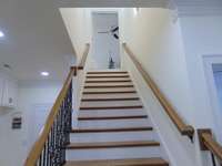 Extra wide stair case up to second floor with hand rails on both sides. Oak stairs and railings with metal spindles.