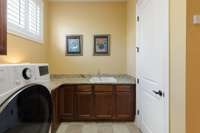 laundry room offers tons of storage with cabinets and closet, plus folding space and a slop sink