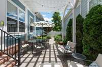 The courtyard looks like something out of a French hotel with paver stone patio, pergola and lush landscaping.