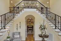 The grand foyer features a stunning dual staircase, setting the tone for the exquisite design throughout.