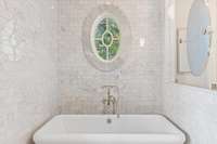 the tub rests across from the shower in marble clad wet area