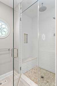 Large walk-in shower with rain shower head and bench.