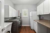 large utility  room has room for secondary fridge, closed storage and a utility sink.