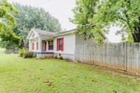 Charming home with a welcoming front porch, vibrant red shutters, and a spacious yard!